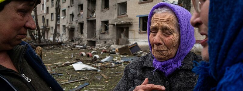 Frauen stehen in Lukiantsi in der Region Charkiw vor einem Haus, das durch einen russischen Luftangriff schwer beschädigt wurde. - Foto: Evgeniy Maloletka/AP/dpa