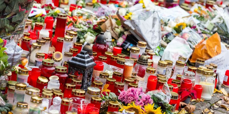 Kerzen und Blumen liegen vor dem Eingang der Waldbachschule. - Foto: Philipp von Ditfurth/dpa