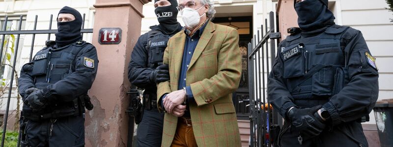 Vermummte Polizisten führen im Dezember 2022 Heinrich XIII. Prinz Reuß in Frankfurt am Main zu einem Polizeifahrzeug. - Foto: Boris Roessler/dpa