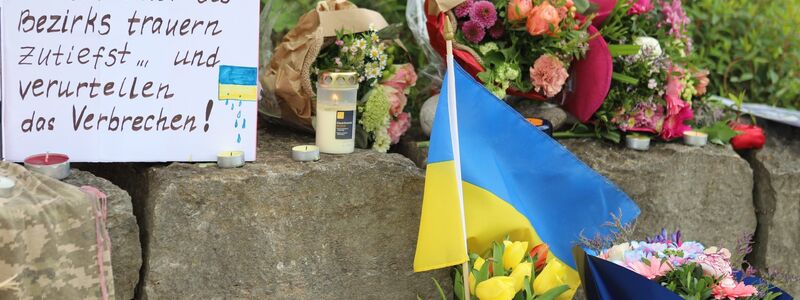 Am Gelände eines Einkaufszentrums, an dem zwei Männer aus der Ukraine getötet worden sind, wurden Blumen niedergelegt sowie eine kleine ukrainische Flagge aufgestellt. - Foto: Constanze Wilz/dpa