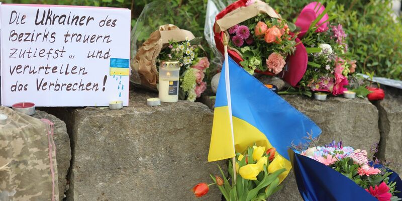 Am Gelände eines Einkaufszentrums, an dem zwei Männer aus der Ukraine getötet worden sind, wurden Blumen niedergelegt sowie eine kleine ukrainische Flagge aufgestellt. - Foto: Constanze Wilz/dpa