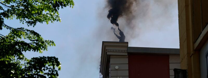 Ein Vermummter brennt auf dem Dach der Roten Flora in Hamburg Pyrotechnik ab. - Foto: Axel Heimken/dpa