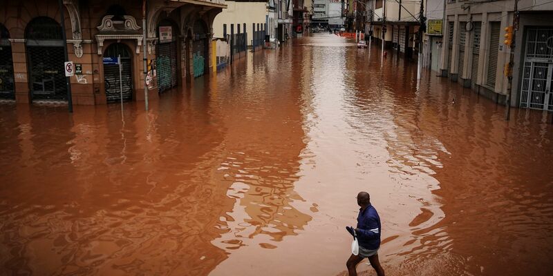 Ein Mann watet in Porto Alegre im brasilianischen Bundesstaat Rio Grande do Sul durch ein von schweren Regenfällen überschwemmtes Gebiet. - Foto: Carlos Macedo/AP/dpa