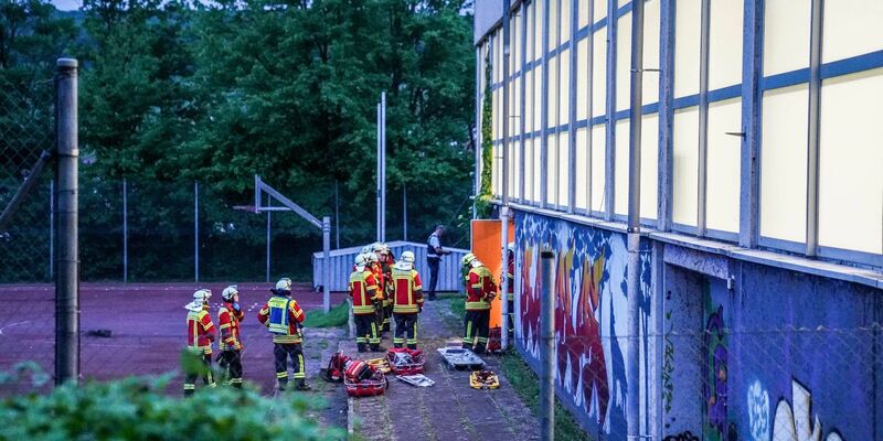 Rettungskräfte stehen vor einer Turnhalle. Vier Kinder sind durch das Dach einer Sporthalle gefallen. - Foto: Kohls/SDMG/dpa