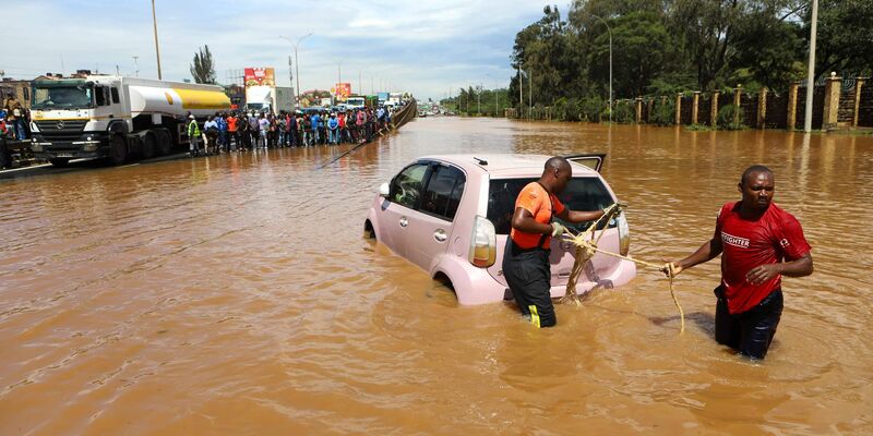 Menschen in Nairobi, die im Hochwasser ein Auto ziehen. - Foto: Joy Nabukewa/XinHua/dpa