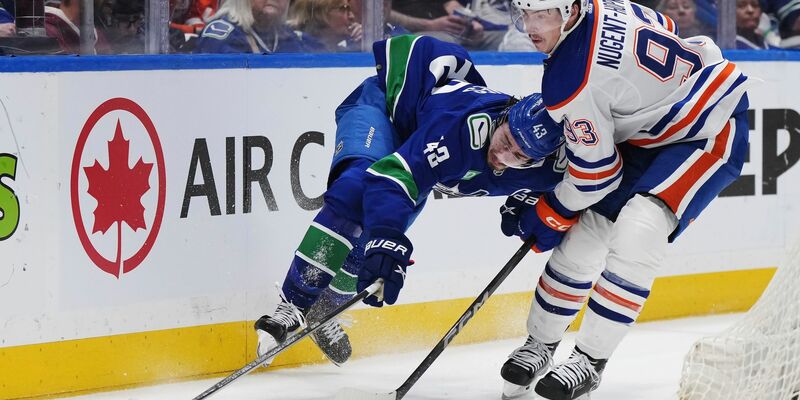 Quinn Hughes von den Vancouver Canucks wird von Ryan Nugent-Hopkins von den Edmonton Oilers zu Fall gebracht. - Foto: Darryl Dyck/The Canadian Press via AP/dpa