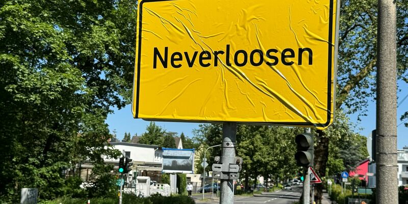 Das Ortsschild von Leverkusen im Stadtteil Schlebusch ist mit der Aufschrift «Neverloosen» überklebt worden. - Foto: Holger Schmidt/dpa