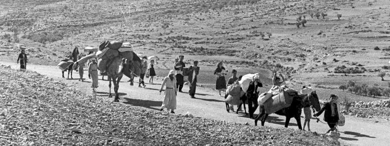 Arabische Flüchtlinge gehen mit ihren Kindern und Habseligkeiten im Gepäck am 9. November 1948 auf einer staubigen Straße von Jerusalem in den Libanon. Die Staatsgründung Israels war 1948 für Hunderttausende von Palästinensern mit Vertreibung und dem Verlust von Heimat verbunden. - Foto: Jim Pringle/AP/dpa