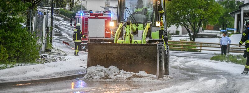 Einsatzkräfte der Feuerwehr räumen nach einem Hagelscheuer eine Straße in Söhnstetten im Landkreis Heidenheim (Baden-Württemberg). - Foto: Jason Tschepljakow/dpa