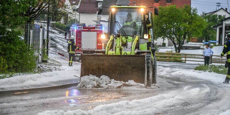 Einsatzkräfte der Feuerwehr räumen nach einem Hagelscheuer eine Straße in Söhnstetten im Landkreis Heidenheim (Baden-Württemberg). - Foto: Jason Tschepljakow/dpa