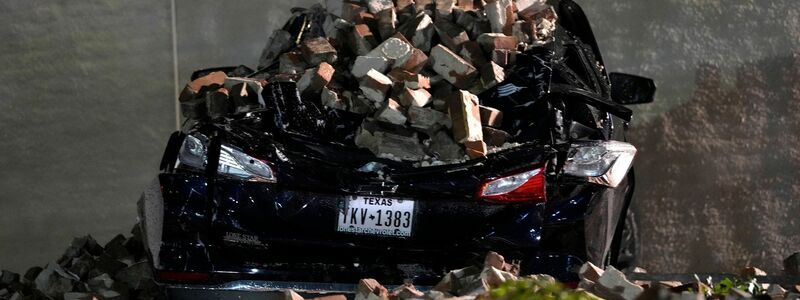 Ein Auto, das von herabfallenden Ziegeln einer umgestürzten Hauswand zerquetscht wurde, steht auf einem Parkplatz in der Innenstadt von Houston. - Foto: David J. Phillip/AP/dpa