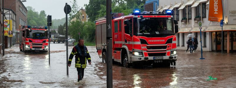Feuerwehrleute bewegen sich durch das Hochwasser in Saarbrücken. - Foto: Harald Tittel/dpa