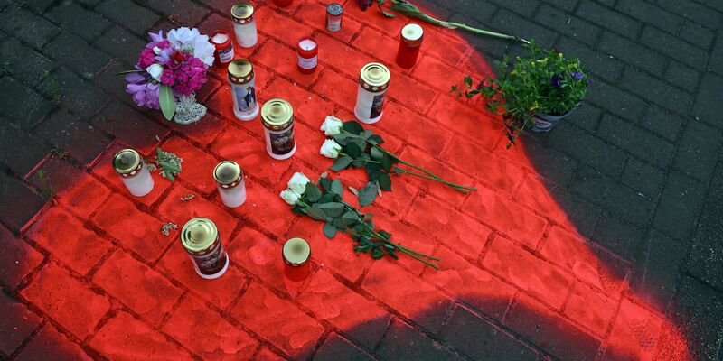 Kerzen und Blumen liegen in einem auf das Pflaster gesprühten roten Herzen in Düsseldorf nach dem mörderischen Brandanschlag. - Foto: Federico Gambarini/dpa
