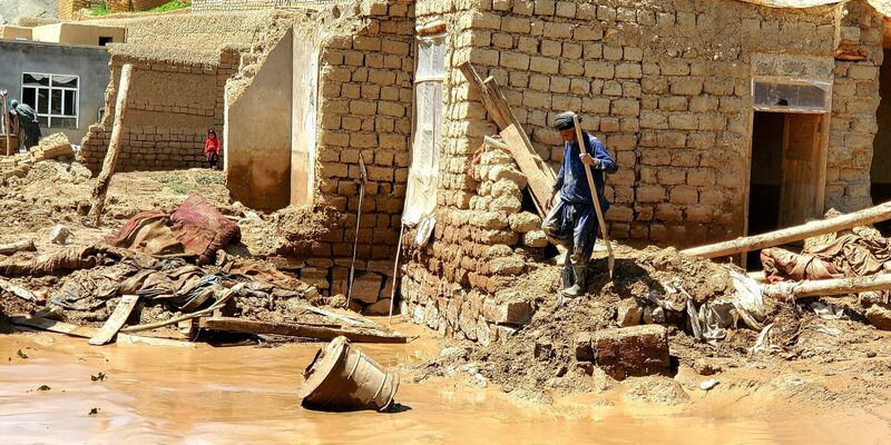 Ein Mann sammelt nach schweren Überschwemmungen in der Provinz Ghor seine Habseligkeiten zusammen. - Foto: Omid Haqjoo/AP/dpa
