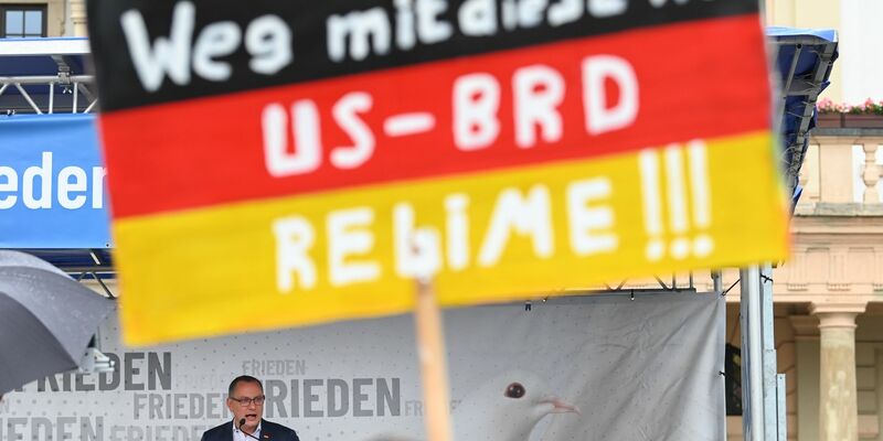 Ein antiamerikanisches Plakat auf einer AfD-Kundgebung mit Bundessprecher Tino Chrupalla in Magdeburg (Archivbild). - Foto: Heiko Rebsch/dpa