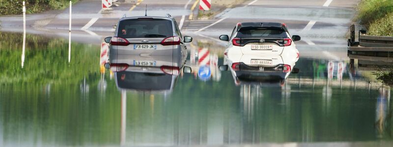 Zwei Autos stehen unter einer Saarbrücke in Saarbrücken im Hochwasser. - Foto: Andreas Arnold/dpa