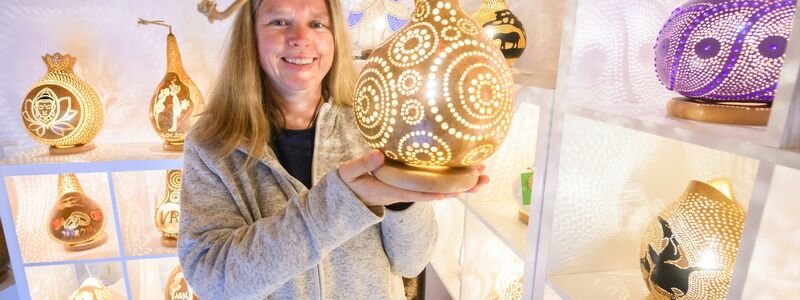 Virginia Lauterbach präsentiert eine ihrer handgefertigten Kürbislampen in der Kalebassenmanufaktur in Bückeburg. - Foto: Julian Stratenschulte/dpa