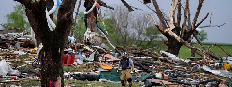 Ein Feuerwehrmann geht in Greenfield, Iowa, durch die Trümmer von Häusern, die vo einem Tornado zerstört wurden. - Foto: Charlie Neibergall/AP/dpa