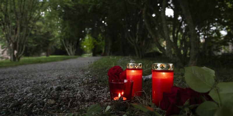 Blumem und Kerzen liegen im Park an dem Tatort im schweizerischen Männedorf. - Foto: Ennio Leanza/KEYSTONE/dpa