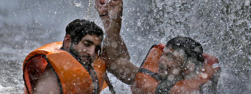 Pakistanische Männer kühlen sich in einem Bach ab, während die Temperaturen in Islamabad 39 Grad Celsius erreichen. - Foto: Anjum Naveed/AP/dpa