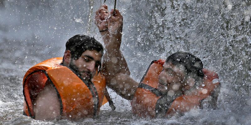 Zwei pakistanische Männer kühlen sich in Islamabad in einem Bach ab. - Foto: Anjum Naveed/AP/dpa