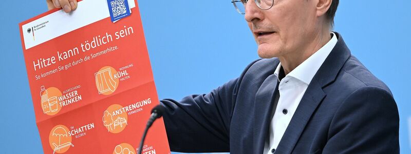 Bundesgesundheitsminister Karl Lauterbach (SPD) hält ein Plakat zum Thema Hitzeschutz hoch. - Foto: Britta Pedersen/dpa