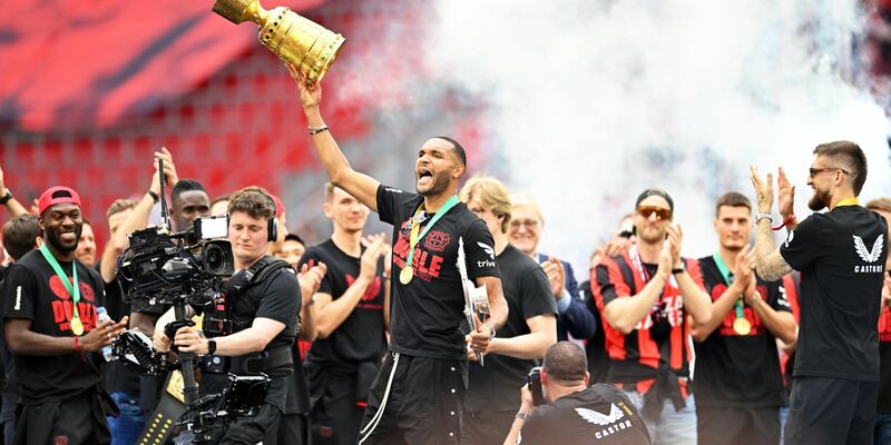 Leverkusens Jonathan Tah (M) präsentiert bei der Meisterfeier in der BayArena die Meisterschale und den Pokal. - Foto: Marius Becker/dpa