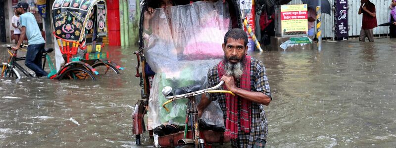 Menschen bewegen sich mühsam durch das Hochwasser in der Stadt Chittagon. - Foto: Mohammed Shajahan/ZUMA Press Wire/dpa