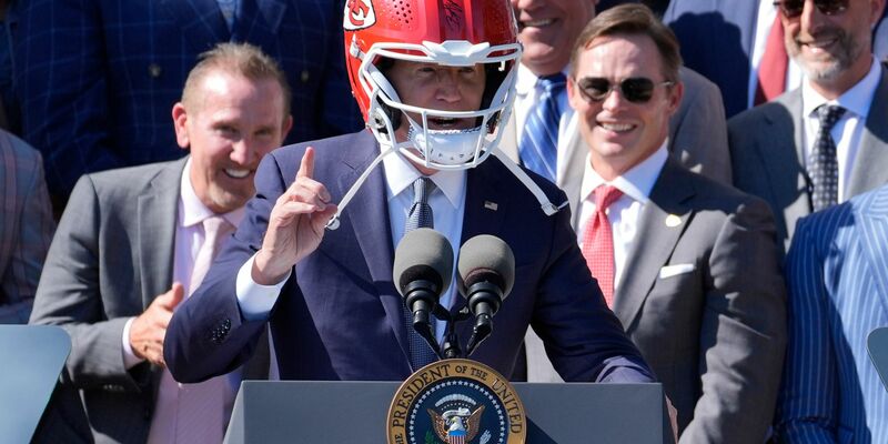 US-Präsident Joe Biden (M) trägt einen Helm von Super-Bowl-Champion Kansas City Chiefs bei einem Besuch im Weißen Haus. - Foto: Evan Vucci/AP/dpa