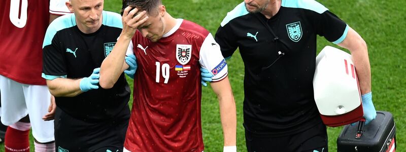 Christoph Baumgartner (M) aus Österreich wird nach einer Verletzung von medizinischen Mitarbeitern vom Spielfeld geführt. - Foto: Mihai Barbu/Pool AFP/AP/dpa