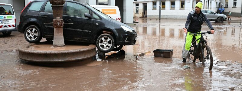 Auf einem Brunnen in Rudersberg steht ein durch ein Hochwasser weggespültes Auto. - Foto: Bernd Weißbrod/dpa