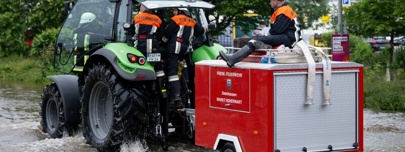 Feuerwehrleute fahren in Reichertshofen über eine überflutete Straße. - Foto: Sven Hoppe/dpa