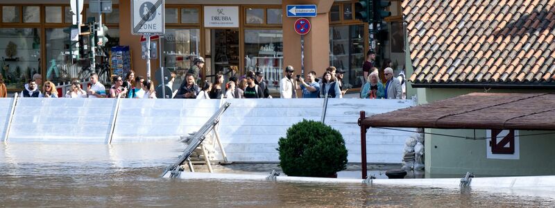 Menschen schauen sich in der Altstadt von Regensburg hinter einer Schutzwand das Hochwasser an. - Foto: Sven Hoppe/dpa