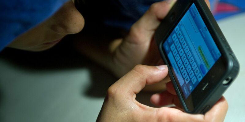 Ein elfjähriger Junge liegt unter der Bettdecke und schreibt auf einem Smartphone eine SMS. Kinder unter 13 Jahren sollten Experten zufolge keinen Zugang zu derartigen Medien haben. - Foto: Patrick Pleul/dpa