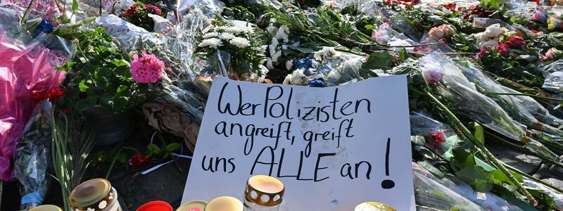 Blumen und Kerzen auf dem Marktplatz in Mannheim zum Gedenken an den getöteten Polizisten. - Foto: Bernd Weißbrod/dpa