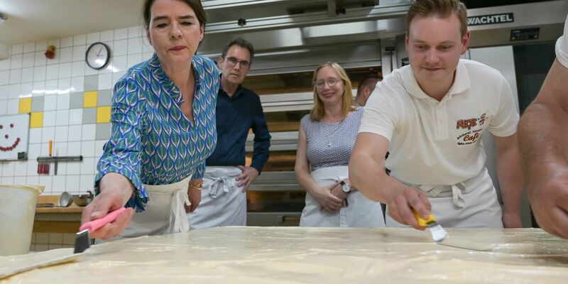 Tagesschau-Sprecherin Susanne Daubner (l) und Bäckermeister Vincent Richter von der Bäckerei Meye verteilen den Sulf-Belag auf dem weltgrößten Mohnkuchen. - Foto: Heiko Rebsch/dpa