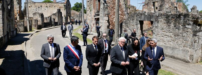 Der französische Präsident Emmanuel Macron und der deutsche Bundespräsident Frank-Walter Steinmeier gehen an Ruinen in Oradour-sur-Glane vorbei. - Foto: Ludovic Marin/AFP Pool/AP/dpa