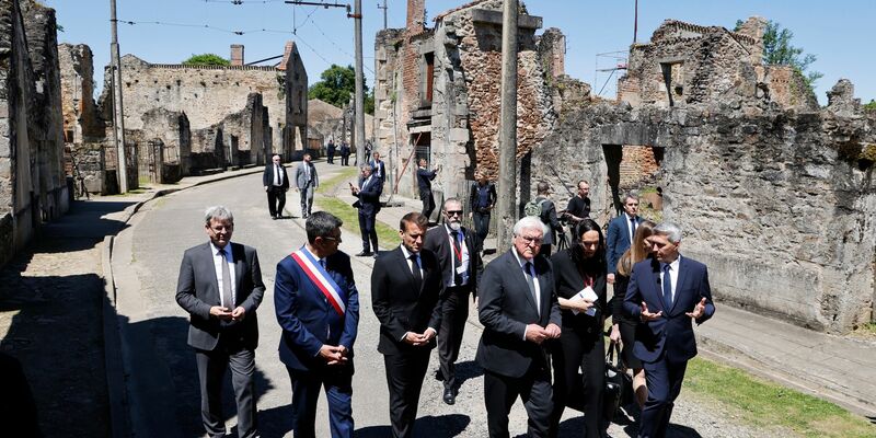 Der französische Präsident Emmanuel Macron und der deutsche Bundespräsident Frank-Walter Steinmeier gehen an Ruinen in Oradour-sur-Glane vorbei. - Foto: Ludovic Marin/AFP Pool/AP/dpa
