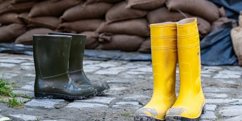 Gummistiefel stehen in der Altstadt vor Sandsäcken. Der Hochwassernachrichtendienst geht von einem baldigen Ende der Hochwasserlage in Bayern aus. - Foto: Armin Weigel/dpa