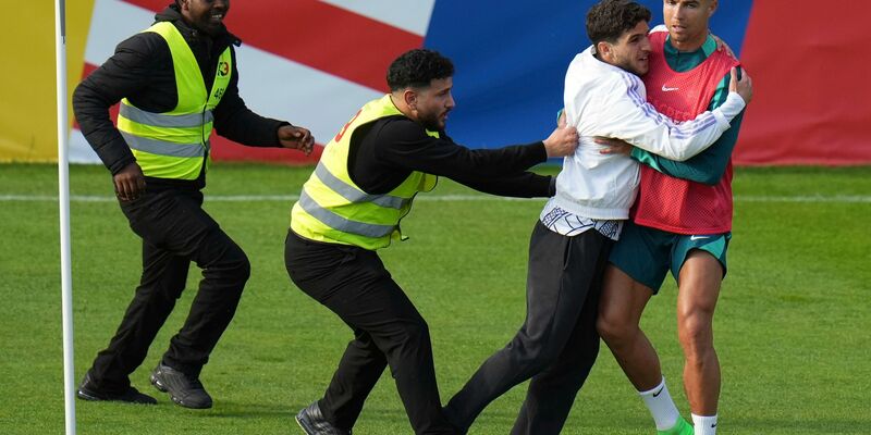 Ein Fan sprintet in Gütersloh auf den Trainingsplatz und umarmt Portugals Superstar Cristiano Ronaldo. - Foto: Hassan Ammar/AP/dpa