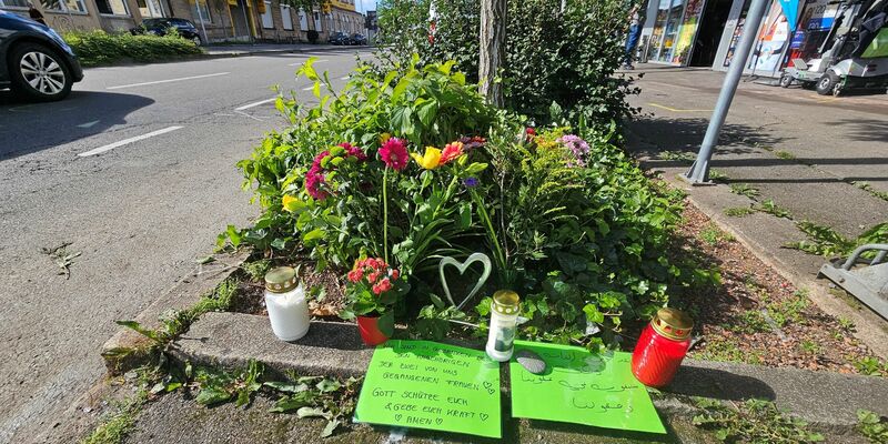 Blumen und Grablichter sind an der Unfallstelle aufgestellt worden. - Foto: Andreas Rosar/dpa