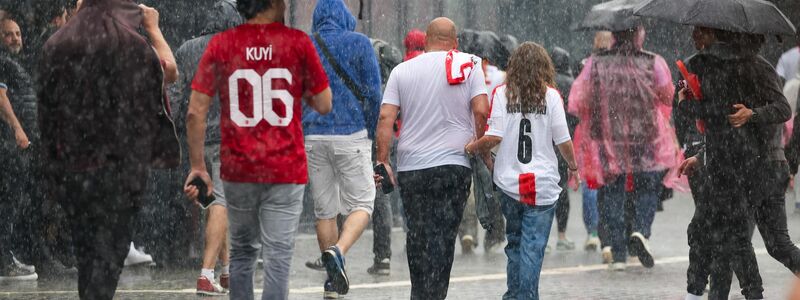 Das haben sie sich sicherlich anders vorgestellt: Fussballfans in Dortmund laufen im strömenden Regen zum Stadion. - Foto: Christoph Reichwein/dpa