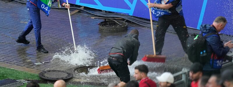 Kampf gegen die Wassermassen: Mitarbeiter sind vor dem Spiel Türkei gegen Georgien im Stadion im Einsatz. - Foto: Andreea Alexandru/AP