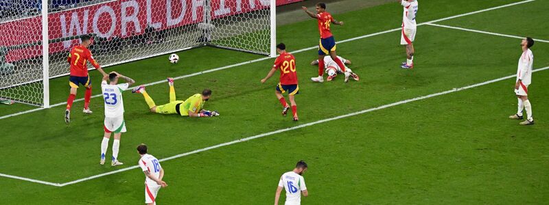 Italiens Torhüter Gianluigi Donnarumma liegt nach dem Gegentor am Boden. Die Spanier jubeln, während die Italiener enttäuscht auf dem Platz stehen. - Foto: Julian Stratenschulte/dpa