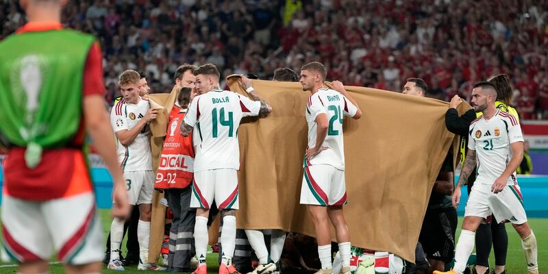 Die ungarischen Spieler halten einen Sichtschutz, während Stürmer Barnabas Varga behandelt wird. - Foto: Antonio Calanni/AP