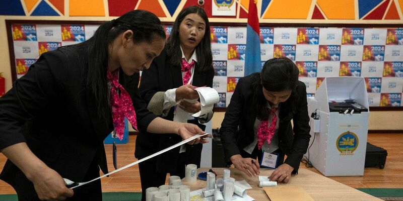 Wahlhelfer überprüfen die Ausdrucke der Ergebnisse von den Stimmauszählungsmaschinen nach Schließung der Wahllokale. - Foto: Ng Han Guan/AP/dpa