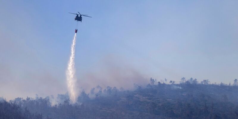 Ein Hubschrauber wirft Wasser auf einen Waldbrand im Norden Athens ab. - Foto: Yorgos Karahalis/AP