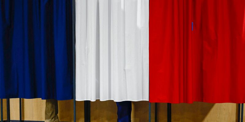 Der französische Präsident Emmanuel Macron und seine Frau Brigitte Macron stehen vor der Stimmabgabe in der Wahlkabine. - Foto: Yara Nardi/Reuters Pool/AP/dpa