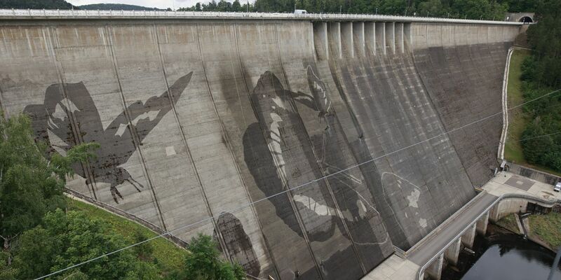Auf der Staumauer der größten Trinkwassertalsperre Deutschlands wird mit Hochdruckreinigern ein Kunstwerk gemalt.  - Foto: Matthias Bein/dpa