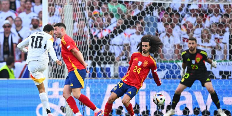 Spaniens Marc Cucurella (M) bekommt den Schuss von Deutschlands Jamal Musiala an den Arm. - Foto: Tom Weller/dpa